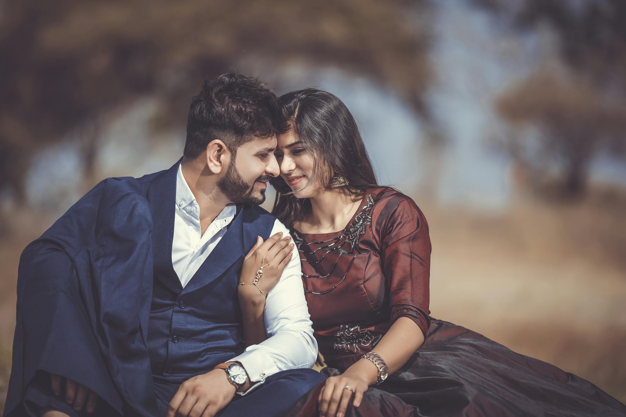 A loving couple sharing a tender moment outdoors, highlighting their romantic connection and stylish attire.
